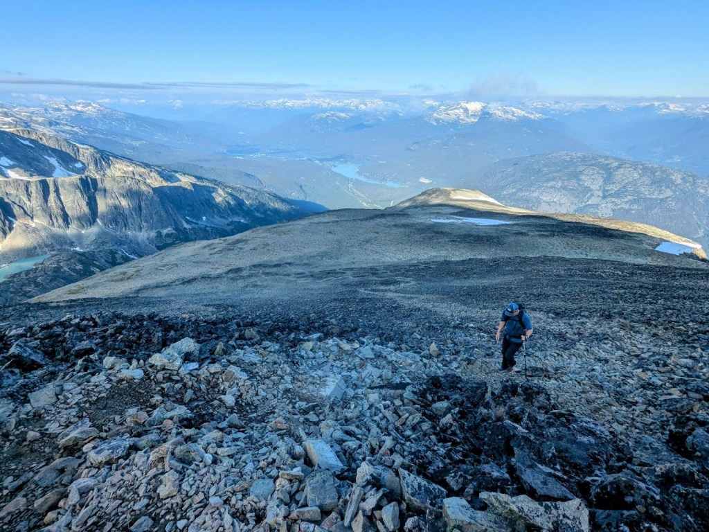 Hiking up Mount Cook on cairn-marked trail through heather and scree above Wedgemount Lake